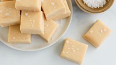 several pieces of cheese on a plate next to some salt