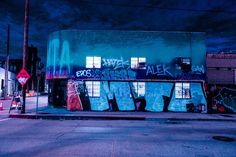 an old building covered in graffiti on the side of a city street at night time