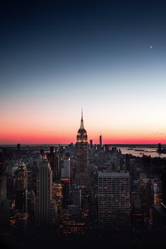 the city skyline is lit up at night, with skyscrapers in the foreground