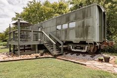 an old train car sitting in the middle of a field with stairs leading up to it