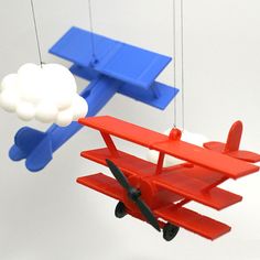 a toy airplane is flying next to a red and blue model plane hanging from strings