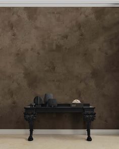 a black table sitting in front of a brown wall with two vases on it