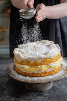 a person sprinkling sugar on top of a cake