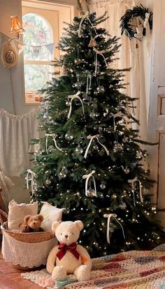 a teddy bear sitting next to a christmas tree