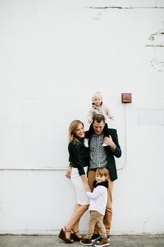 a family standing in front of a white wall