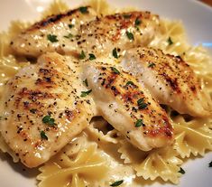 two pieces of chicken on top of pasta with parmesan sprinkles