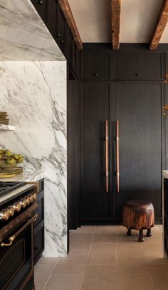 a kitchen with marble counter tops and black cabinets, along with an oven in the center