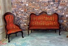 two red chairs sitting next to each other in front of a brick wall with flowers on it