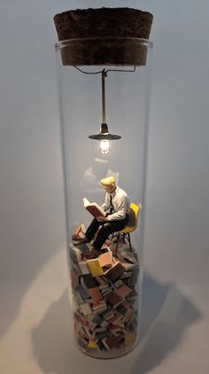 a person sitting on a chair under a light bulb in a jar filled with books