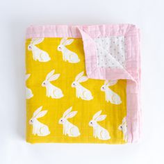 a yellow and pink blanket with white rabbits on it