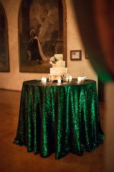 a table with a cake and candles on it in the middle of a room that is decorated with green sequins