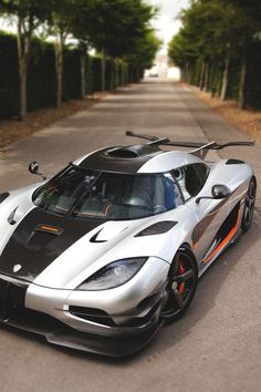 a silver and black sports car driving down a road