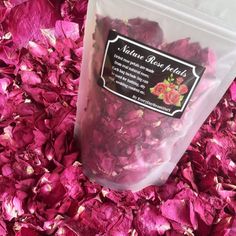 a bag of dried rose petals sitting on top of a bed of pink flowers in a pile