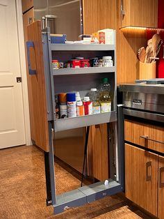 an open cabinet in the middle of a kitchen with lots of spices and condiments