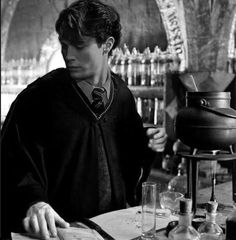 a man sitting at a table in front of a book and some glasses on it