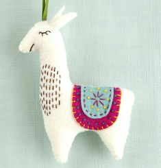 a white llama ornament hanging on a blue wall with a flower in it's mouth