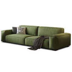 a green couch sitting on top of a white floor next to a throw blanket and pillows