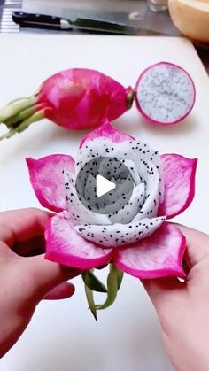 someone is holding a fake flower in front of some other flowers on a white surface