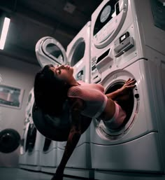 a woman laying on top of a washing machine