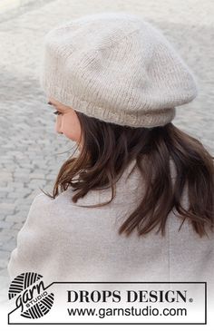 a woman wearing a white knitted hat looking down at the ground with her back to the camera