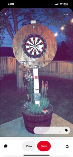 a dart board mounted to the side of a wooden barrel with plants in front of it