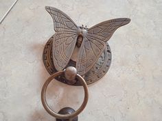 a metal butterfly sculpture on top of a tile floor next to a circular door knocker