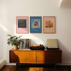 a record player sitting on top of a wooden cabinet next to a potted plant