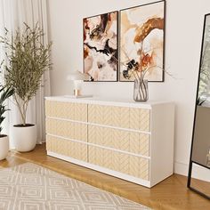 a white dresser sitting next to a mirror on top of a hard wood floored floor