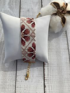 the beaded bracelet is sitting on top of a white pillow with a gold chain