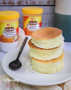 a stack of pancakes sitting on top of a white plate next to yogurt