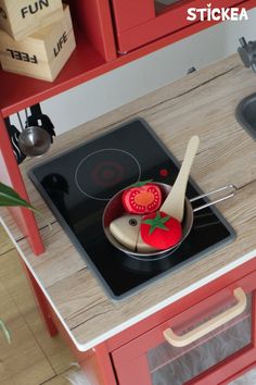 a small kitchen with red cabinets and an electric stove top burner that has a tomato on it