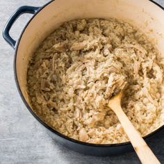 a large pot filled with rice next to a wooden spoon on top of a table