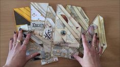 a woman's hands holding onto several pieces of scrap paper on top of a wooden table