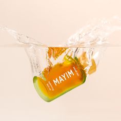 an orange and yellow bottle floating in water with the word mmm on it's side