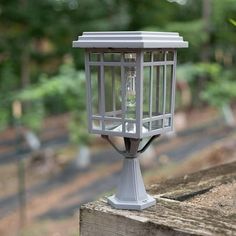 a bird feeder sitting on top of a wooden fence