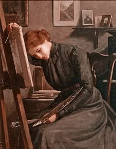 a woman is sitting in front of an easel with her head down and holding a paintbrush