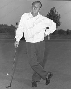 an old black and white photo of a man holding a golf club in his hand