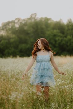 a woman standing in tall grass with her arms outstretched