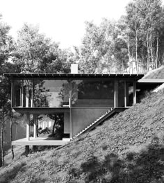 a black and white photo of a house on a hill with trees in the background