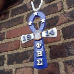 a blue and white cross hanging from the side of a brick wall