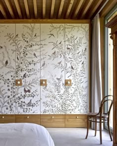 a bed sitting under a wooden ceiling next to a wall covered in birds and flowers