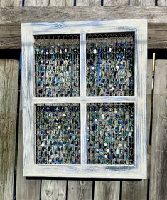 an old window is made out of glass beads and wood planks on the side of a wooden fence