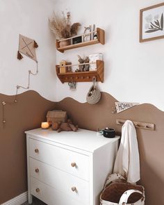 a white dresser sitting in a bedroom next to a wall mounted shelf filled with items