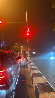 several cars are stopped at an intersection in the night time, with red lights shining on them