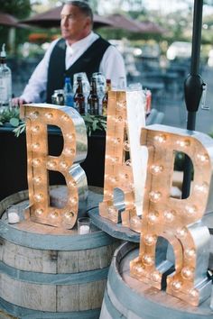 the letters are made out of wood and have light bulbs on them, while an older man stands in the background