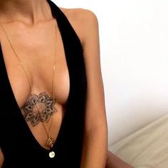 a woman with tattoos on her chest wearing a black dress