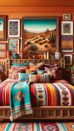 a bed with colorful blankets and pillows in a room filled with pictures on the wall