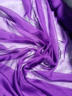 the purple fabric is laying on the white sheet