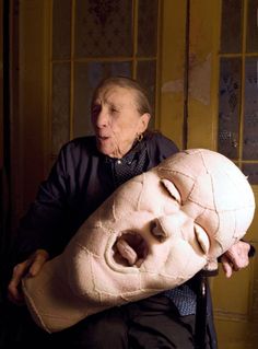 an old man holding a large mask in front of his face