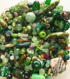 a bowl filled with lots of different types of glass beads and other colorful things on top of it